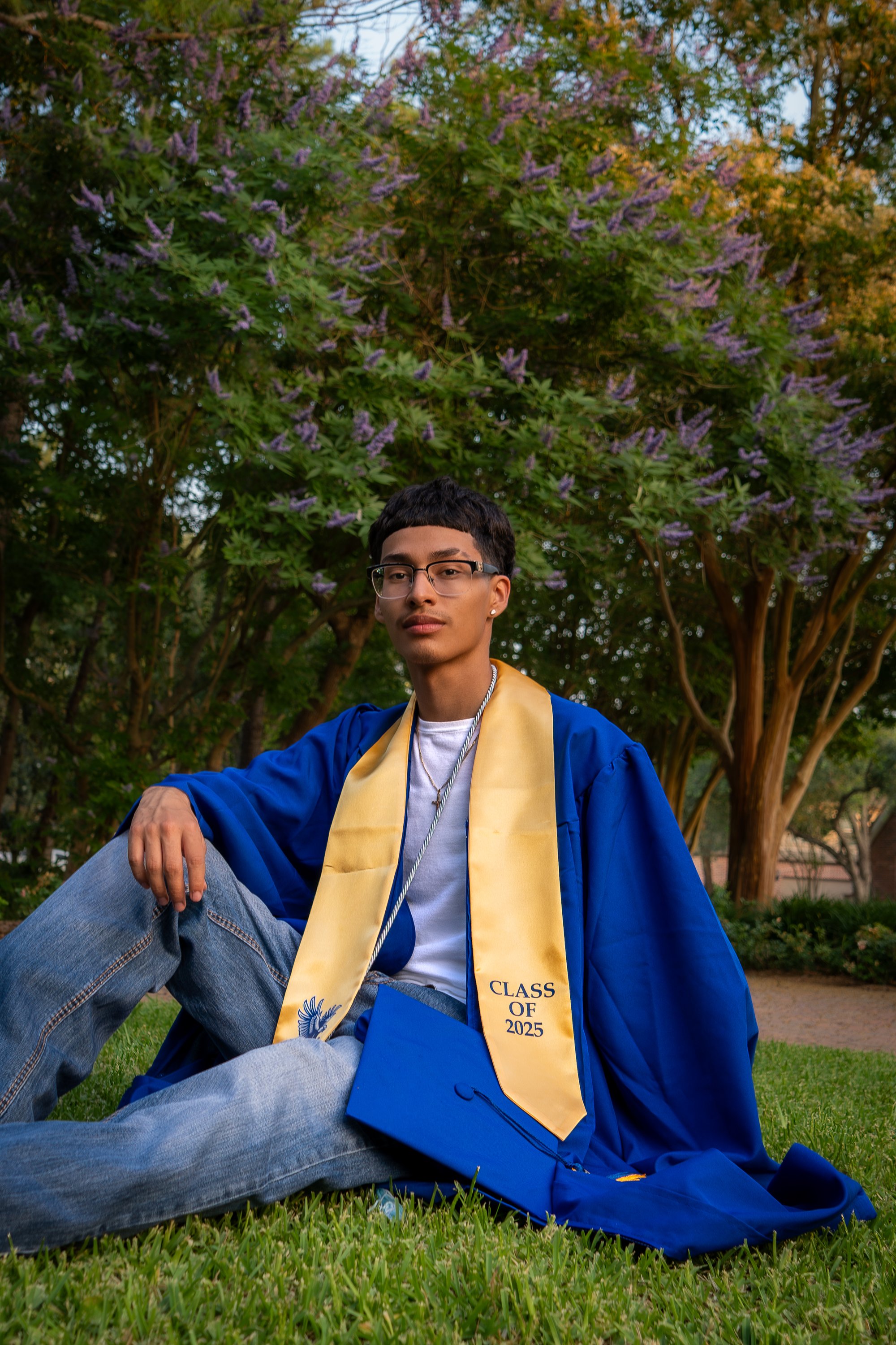 Graduate in blue gown seated on stone bridge