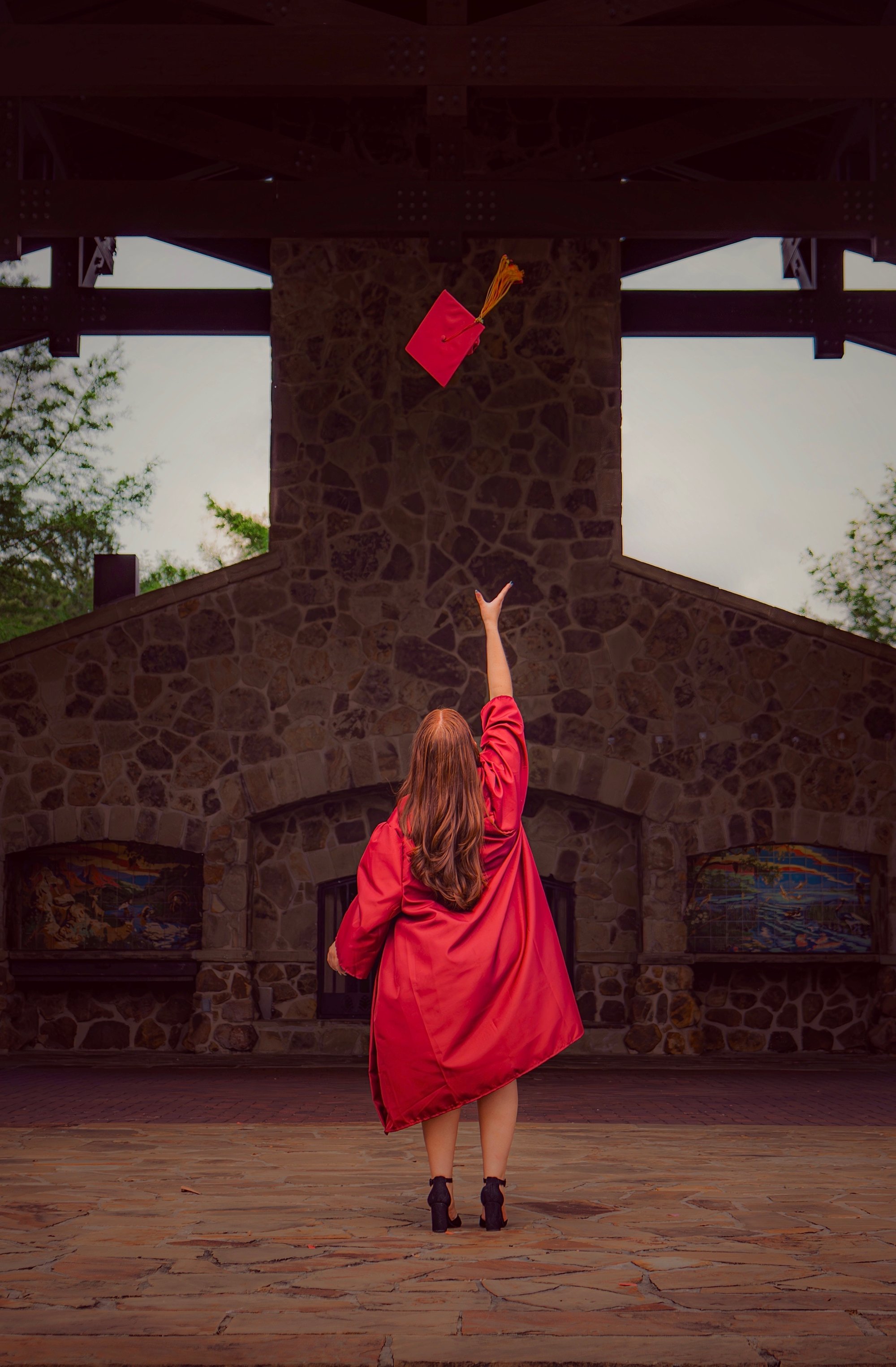 Graduate tossing cap in the air, maroon gown